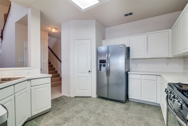 kitchen featuring decorative backsplash, appliances with stainless steel finishes, white cabinetry, and light tile patterned flooring