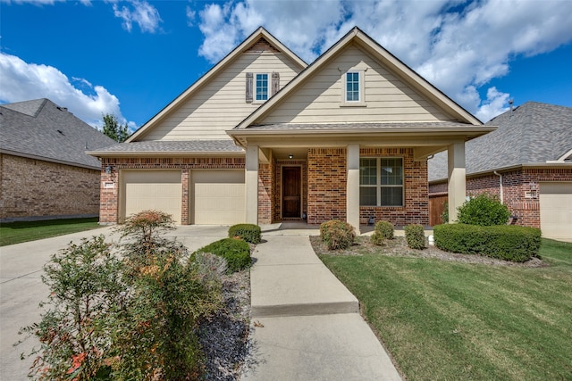 view of front of property featuring covered porch, a garage, and a front lawn