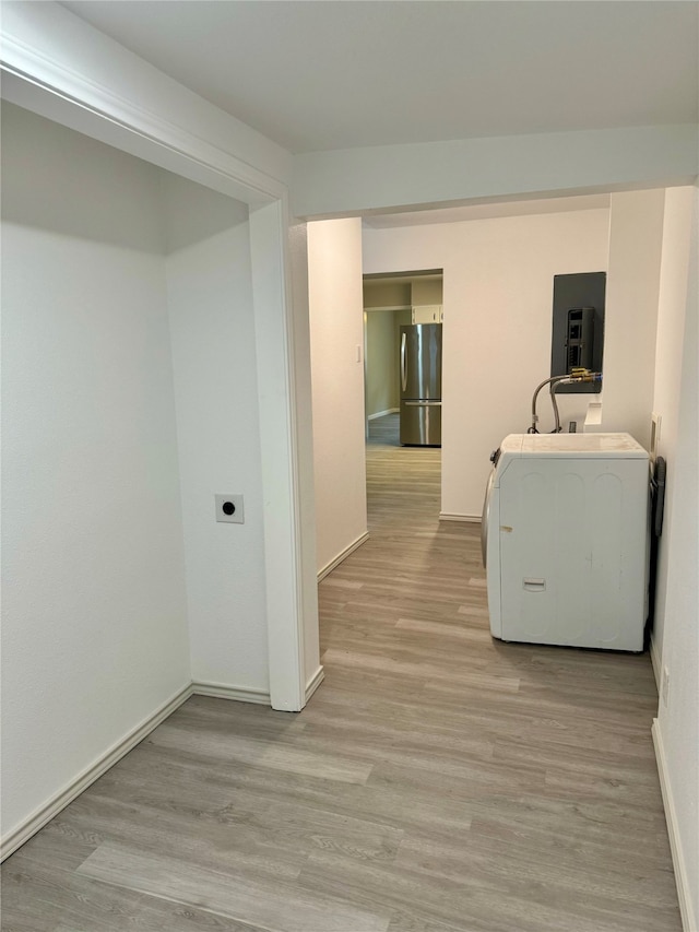 clothes washing area featuring electric panel, washer / dryer, and light hardwood / wood-style floors