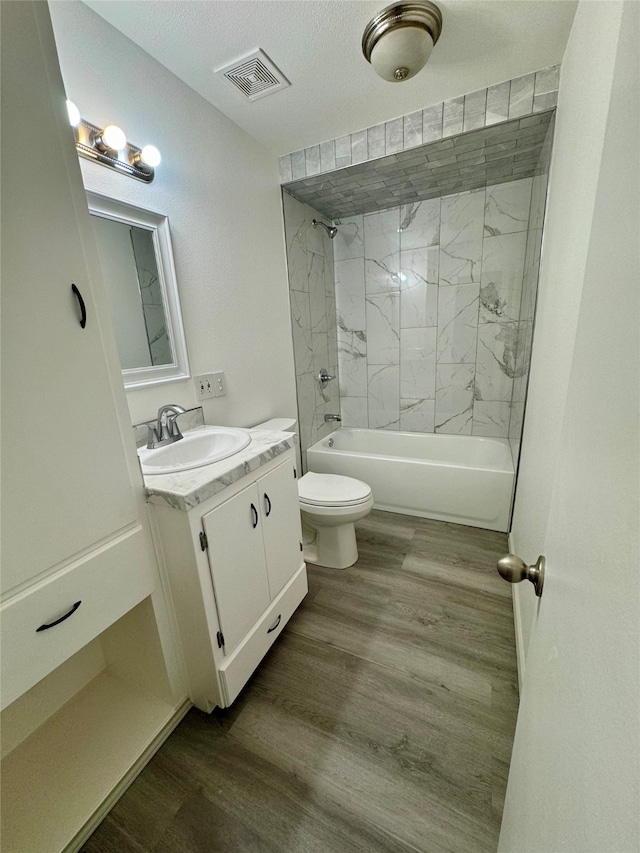 full bathroom featuring toilet, tiled shower / bath, vanity, a textured ceiling, and wood-type flooring