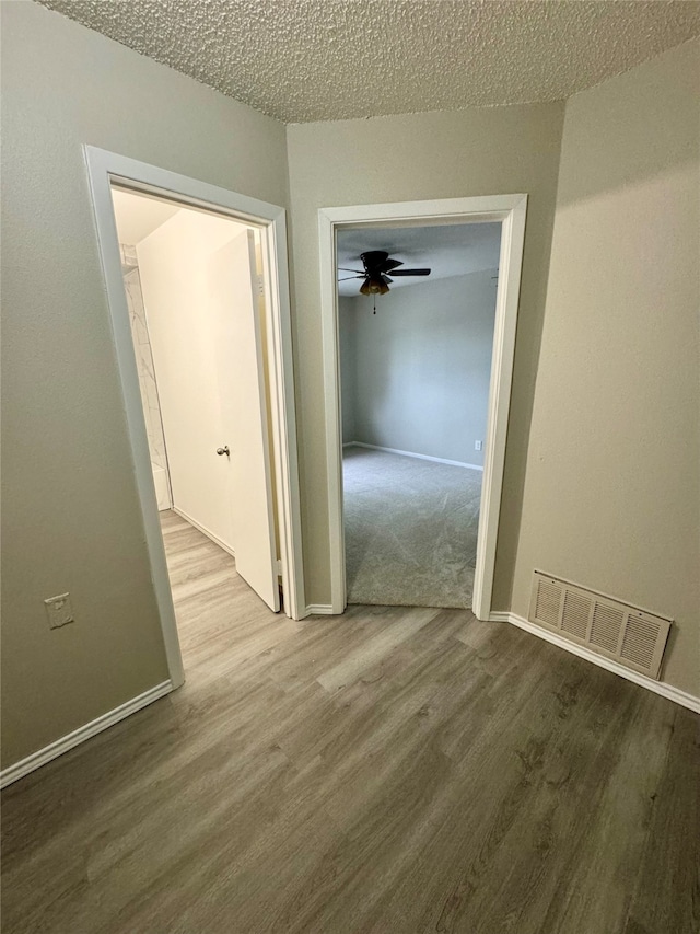 hallway with a textured ceiling and wood-type flooring