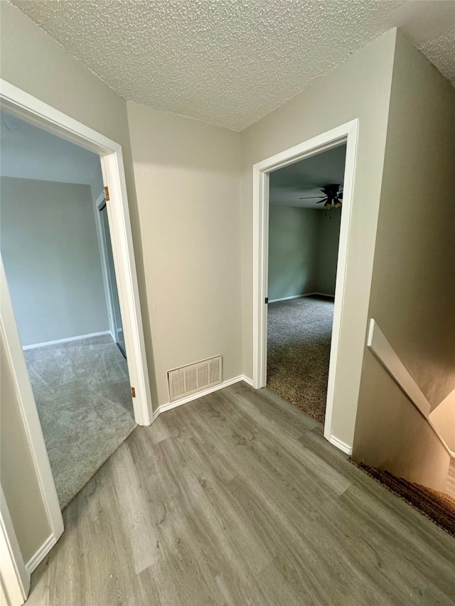 hallway with light colored carpet and a textured ceiling