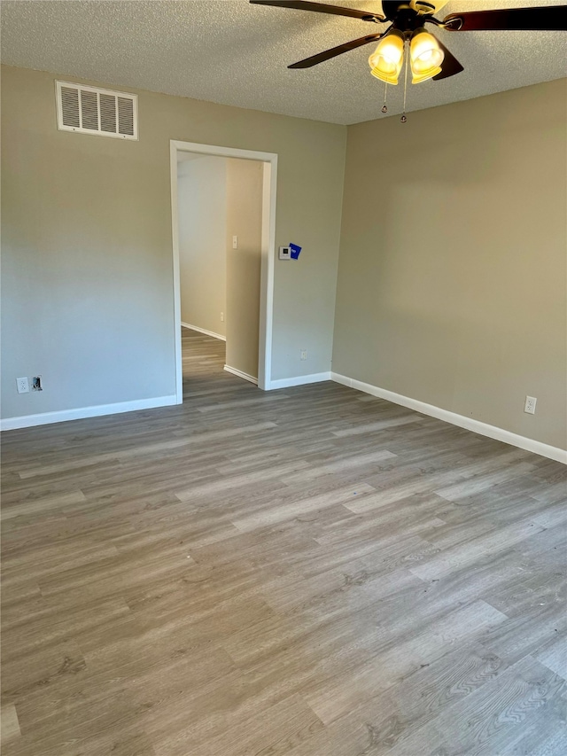 empty room featuring light wood-type flooring, ceiling fan, and a textured ceiling