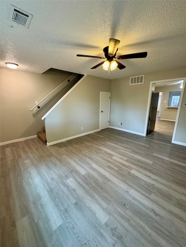 interior space featuring a textured ceiling, light hardwood / wood-style flooring, and ceiling fan