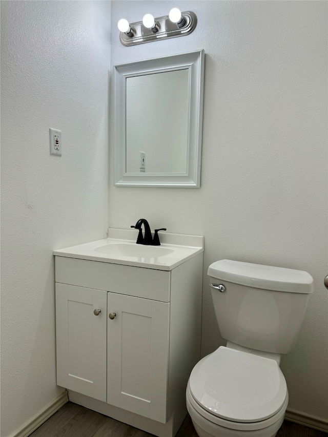 bathroom with vanity, toilet, and hardwood / wood-style floors