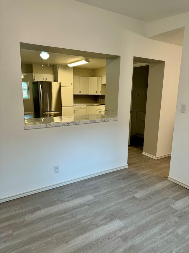 kitchen with stainless steel fridge, light hardwood / wood-style flooring, kitchen peninsula, and white cabinets