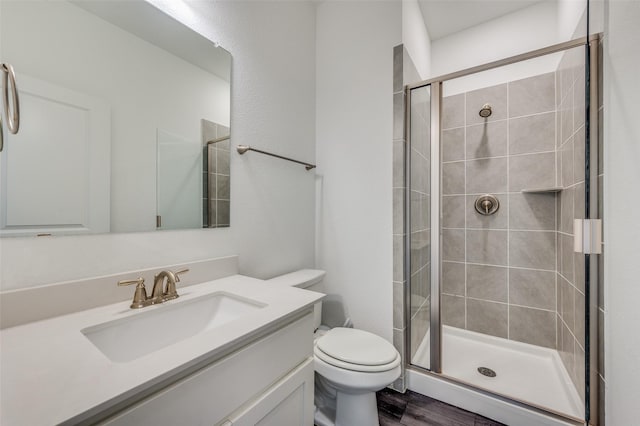 bathroom with an enclosed shower, vanity, hardwood / wood-style floors, and toilet