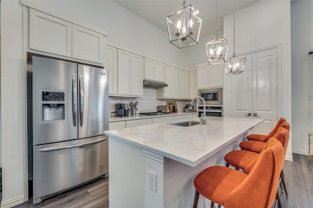 kitchen featuring sink, white cabinetry, a center island with sink, appliances with stainless steel finishes, and pendant lighting