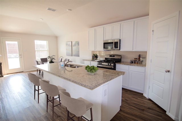 kitchen featuring white cabinets, a kitchen island with sink, stainless steel appliances, and vaulted ceiling