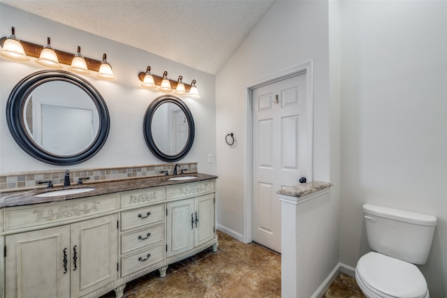 bathroom with lofted ceiling, vanity, toilet, and a textured ceiling