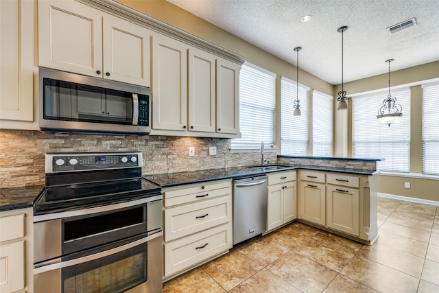 kitchen with a wealth of natural light, stainless steel appliances, and cream cabinetry