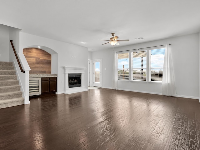 unfurnished living room featuring dark hardwood / wood-style flooring, ceiling fan, and wine cooler