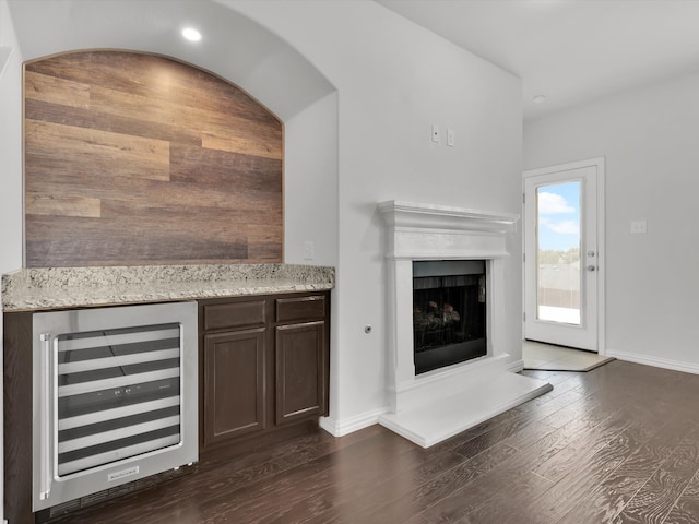 unfurnished living room with beverage cooler, dark hardwood / wood-style flooring, and indoor bar