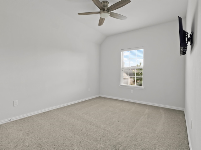 spare room featuring light carpet, vaulted ceiling, and ceiling fan