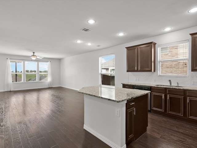 kitchen featuring dishwasher, sink, dark wood-type flooring, and light stone countertops