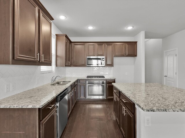 kitchen featuring light stone counters, tasteful backsplash, dark wood-type flooring, sink, and appliances with stainless steel finishes