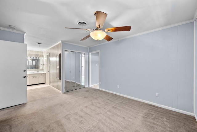 unfurnished bedroom featuring crown molding, ceiling fan, a closet, and light colored carpet