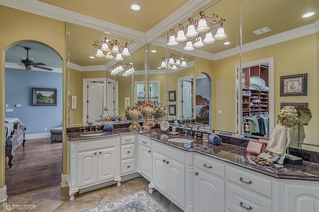 bedroom featuring built in desk, crown molding, ceiling fan, ensuite bathroom, and hardwood / wood-style floors