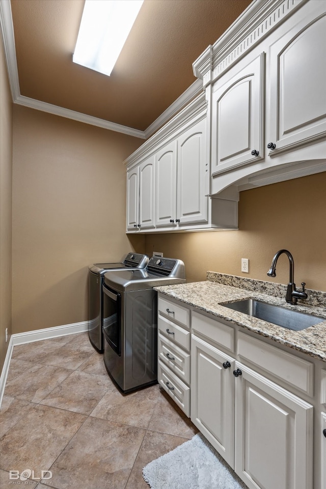 clothes washing area featuring ornamental molding, cabinets, separate washer and dryer, and sink