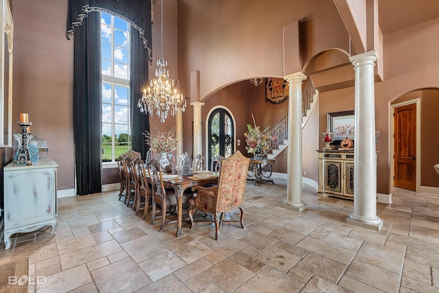 dining room with a notable chandelier, a towering ceiling, and decorative columns