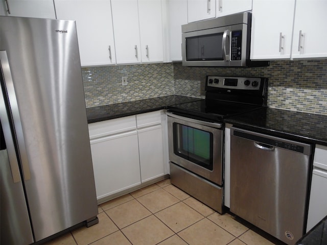 kitchen with dark stone counters, light tile patterned flooring, stainless steel appliances, and white cabinets