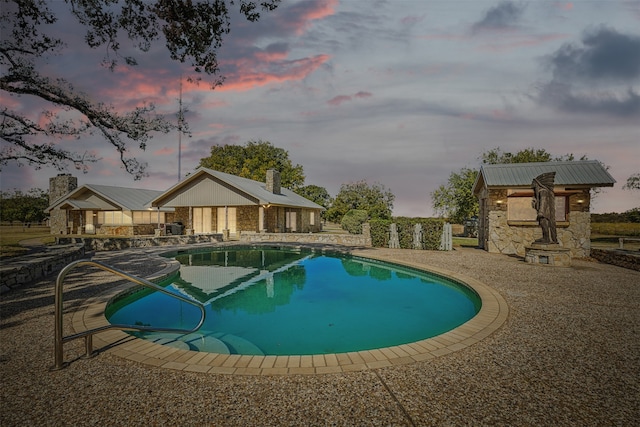 pool at dusk with a patio area