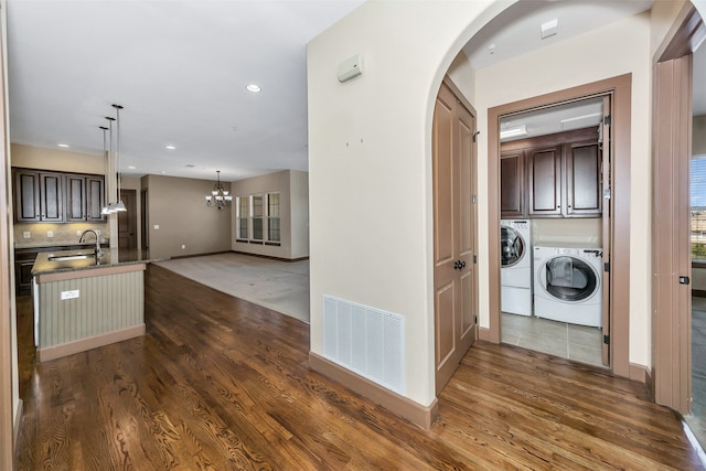 laundry room with dark hardwood / wood-style floors, cabinets, separate washer and dryer, sink, and a chandelier