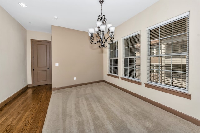 spare room featuring a chandelier and hardwood / wood-style flooring