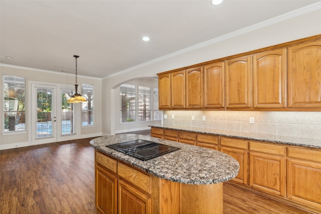 kitchen with a wealth of natural light, a center island, hardwood / wood-style flooring, and black stovetop