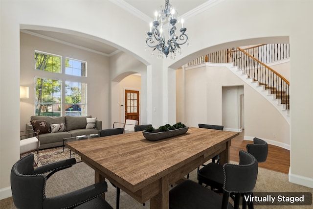 dining space with an inviting chandelier, light wood-type flooring, a high ceiling, and crown molding