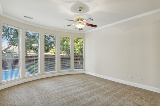 carpeted empty room with ceiling fan, ornamental molding, and a wealth of natural light