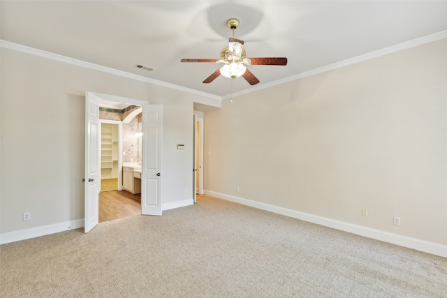 unfurnished bedroom with ornamental molding, ensuite bathroom, ceiling fan, and light colored carpet