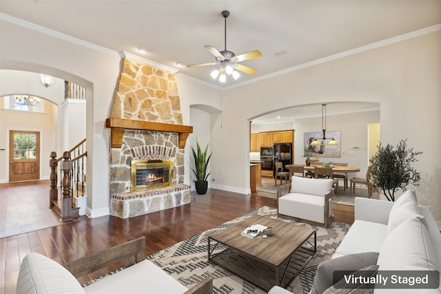 living room featuring a fireplace, ornamental molding, dark hardwood / wood-style flooring, and ceiling fan