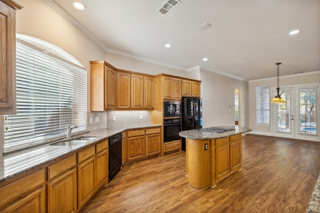 kitchen featuring ornamental molding, a center island, light hardwood / wood-style floors, and black appliances