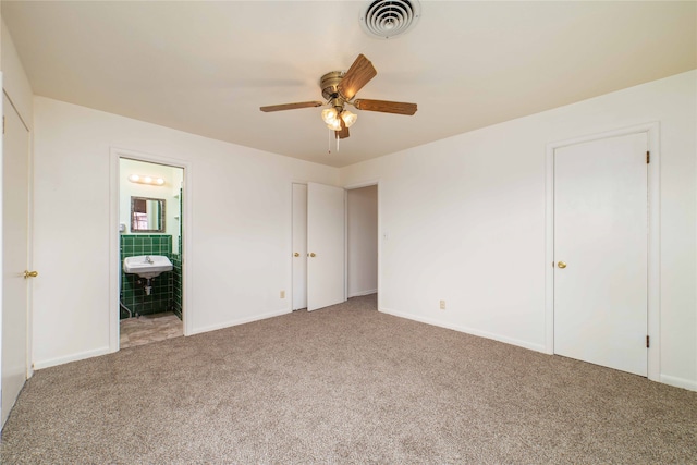 unfurnished bedroom featuring carpet, ensuite bath, and ceiling fan