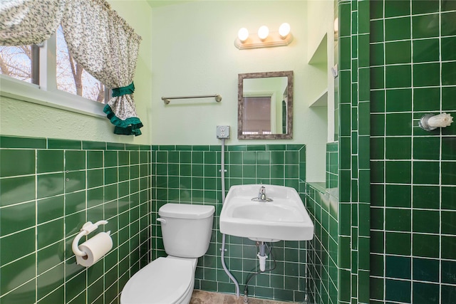 bathroom featuring tile walls, toilet, and sink