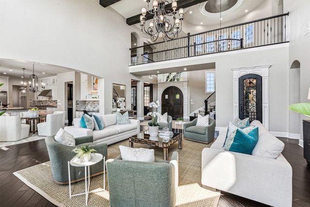 living room featuring an inviting chandelier, stairs, baseboards, a towering ceiling, and arched walkways