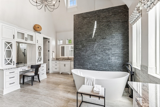 bathroom featuring a towering ceiling, a washtub, vanity, and tile walls