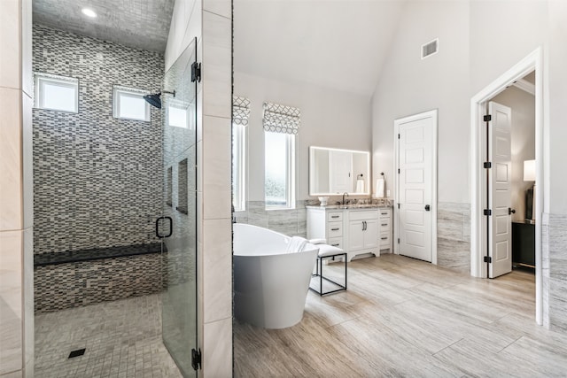 bathroom featuring tile walls, vaulted ceiling, vanity, and independent shower and bath