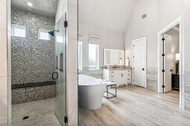 bathroom featuring visible vents, vanity, a freestanding bath, and tile walls