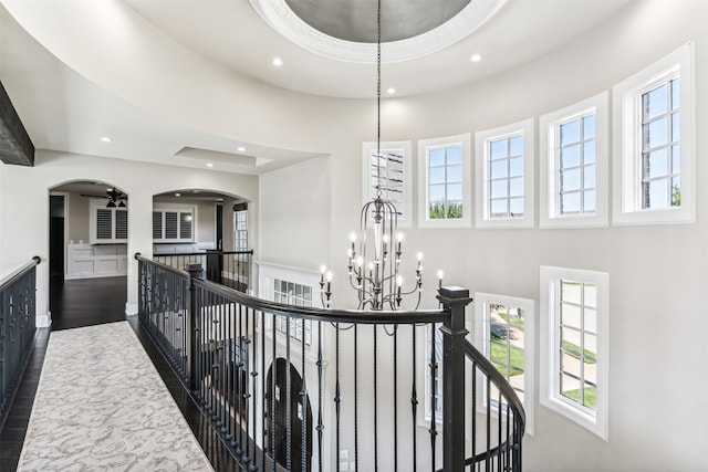 corridor featuring a towering ceiling, dark hardwood / wood-style floors, and a notable chandelier