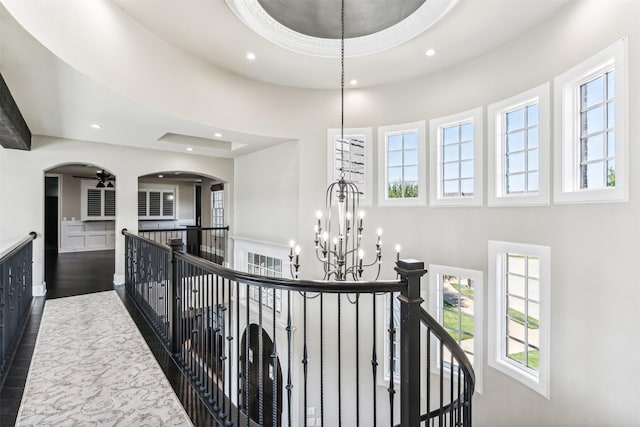 hallway with a healthy amount of sunlight, recessed lighting, a notable chandelier, and an upstairs landing