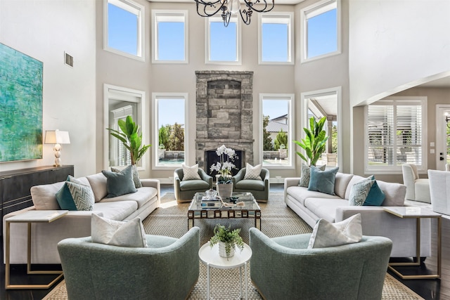 living room featuring a high ceiling, a wealth of natural light, an inviting chandelier, and wood-type flooring