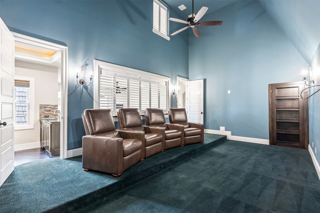 carpeted home theater room with high vaulted ceiling and ceiling fan