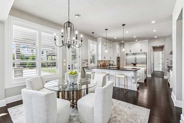 dining space featuring a notable chandelier, sink, and dark hardwood / wood-style flooring