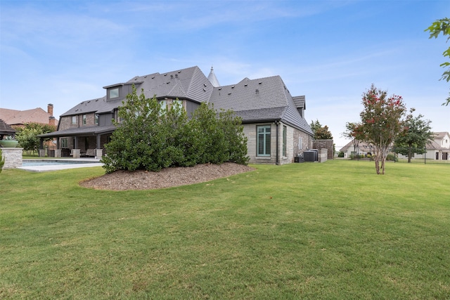 rear view of property with a yard, cooling unit, and a patio