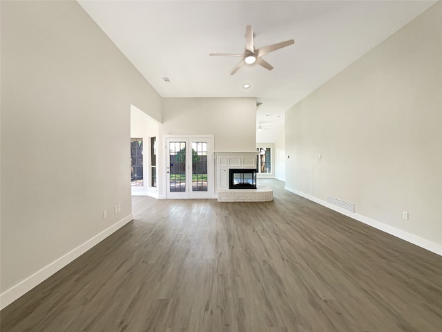 unfurnished living room with dark wood-type flooring, ceiling fan, and a brick fireplace