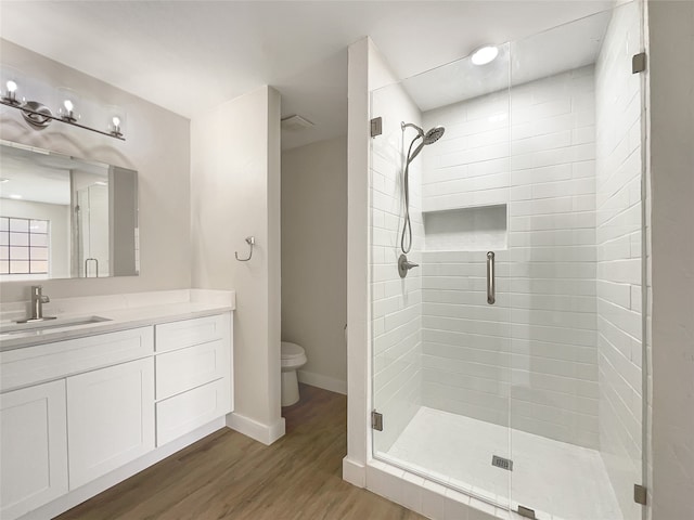 bathroom with toilet, a shower with door, hardwood / wood-style flooring, and vanity