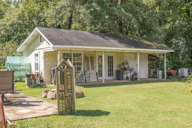 rear view of property featuring an outdoor structure, a patio area, and a yard