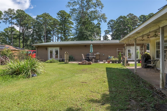 rear view of house with french doors, ceiling fan, a lawn, and a patio area